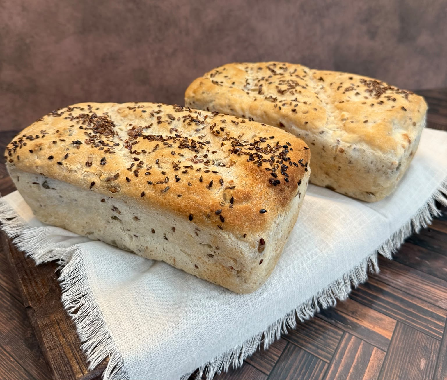 Two seeded gluten-free loaves on white linen