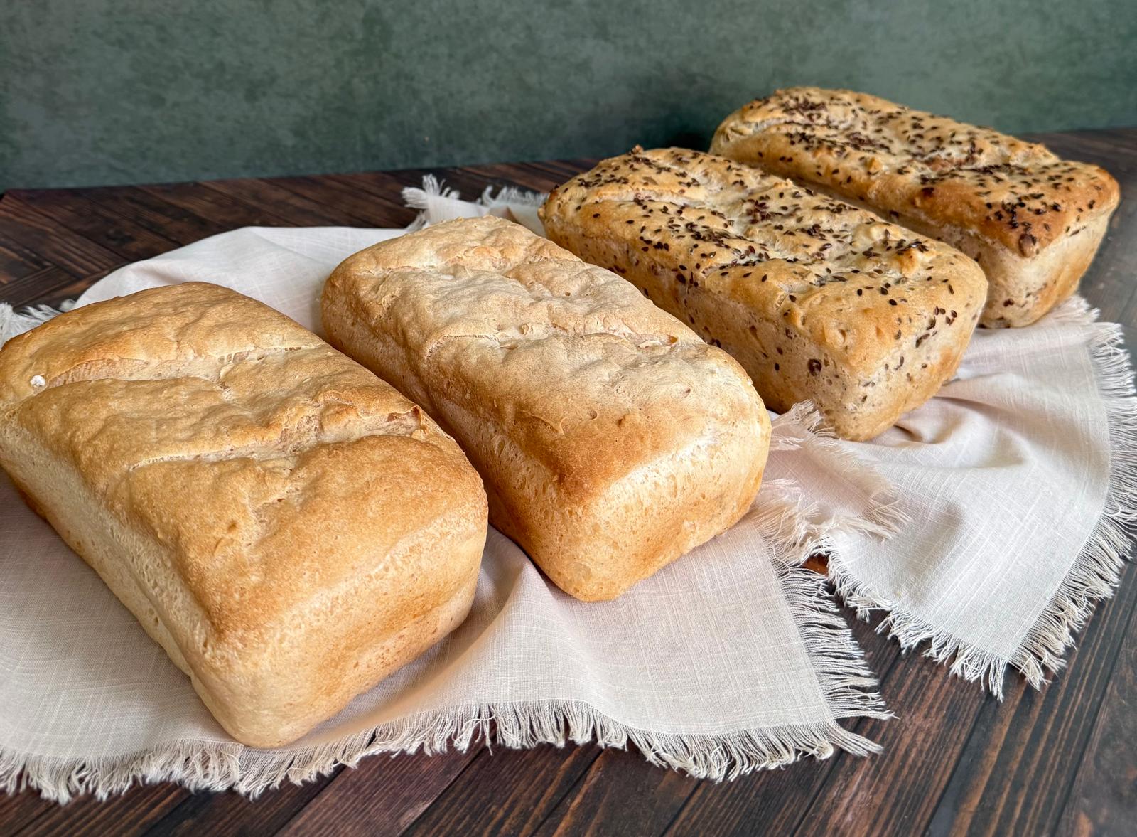 Four gluten-free loaves, plain and seeded, on linen
