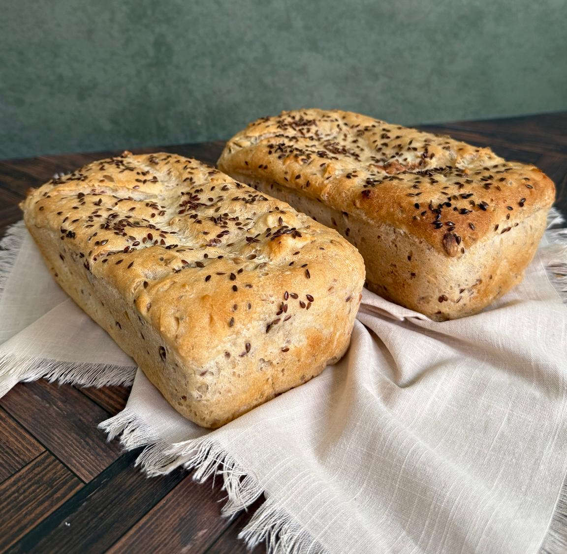 Two seeded gluten-free loaves on linen
