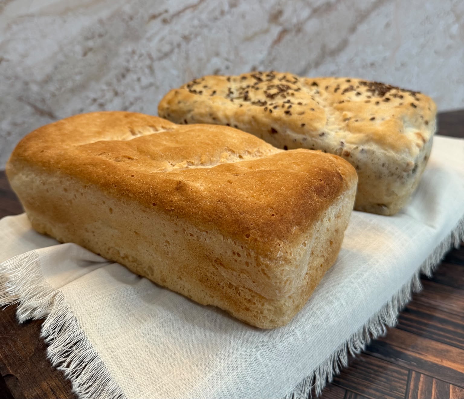 A plain and a seeded gluten-free loaf on linen