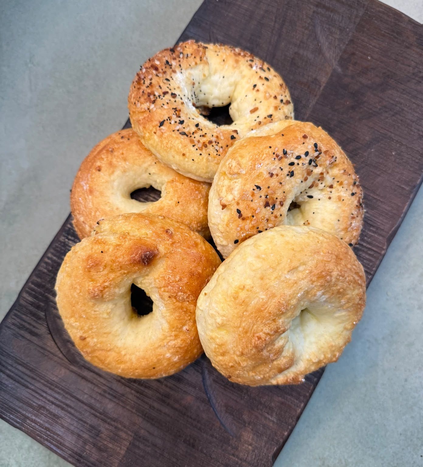 Plain and everything bagels on a wooden board