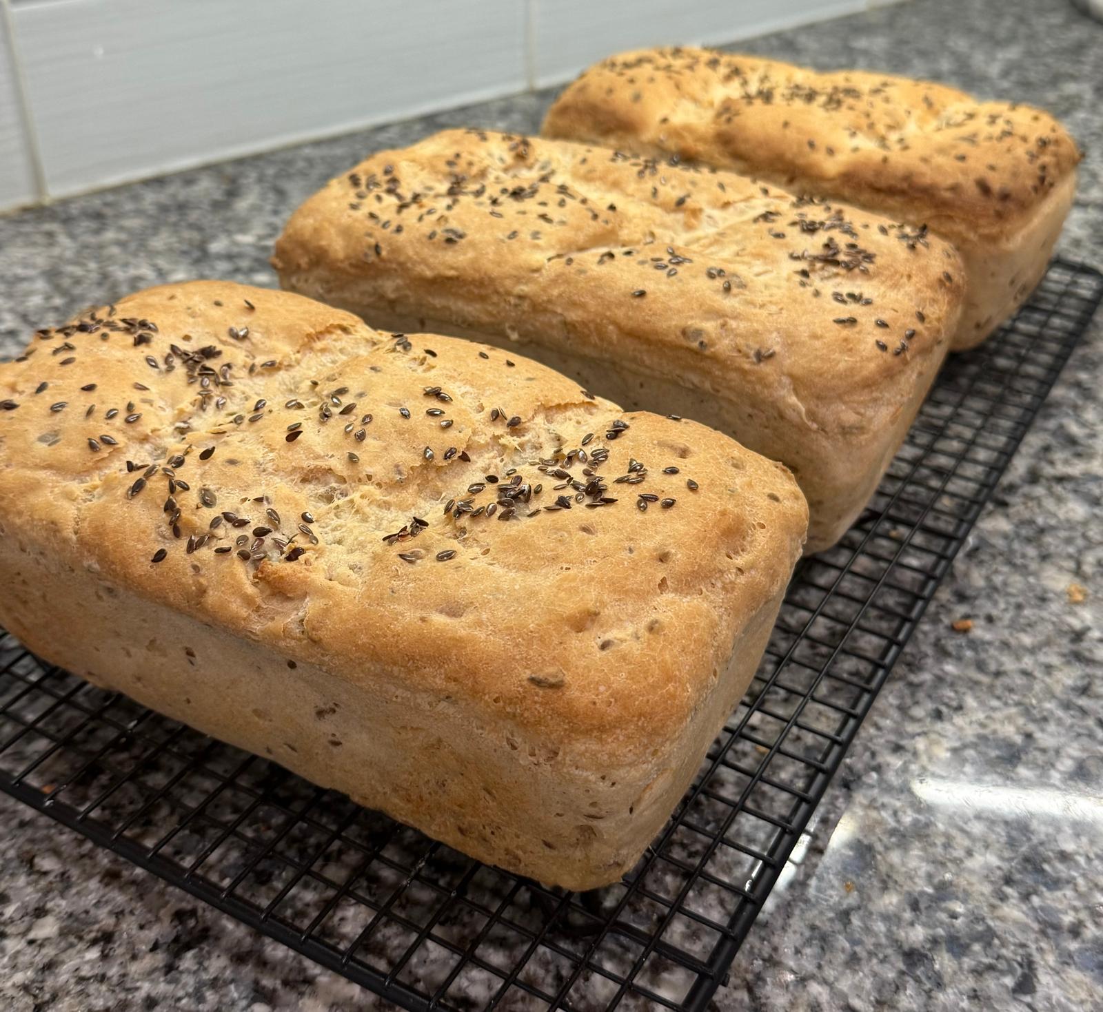 Flax-topped gluten-free loaves cooling on a rack