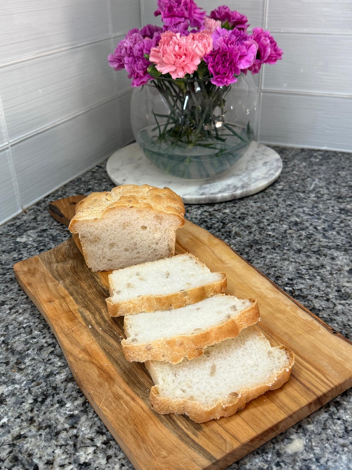 Sliced gluten-free loaf on a board with flowers
