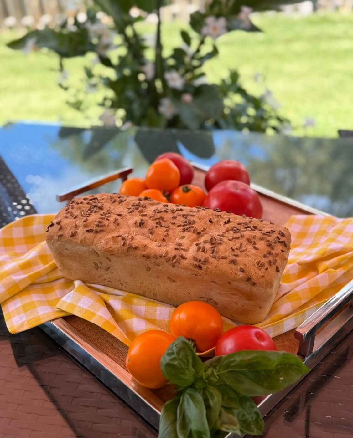 A gluten-free loaf on a garden tray with tomatoes and basil