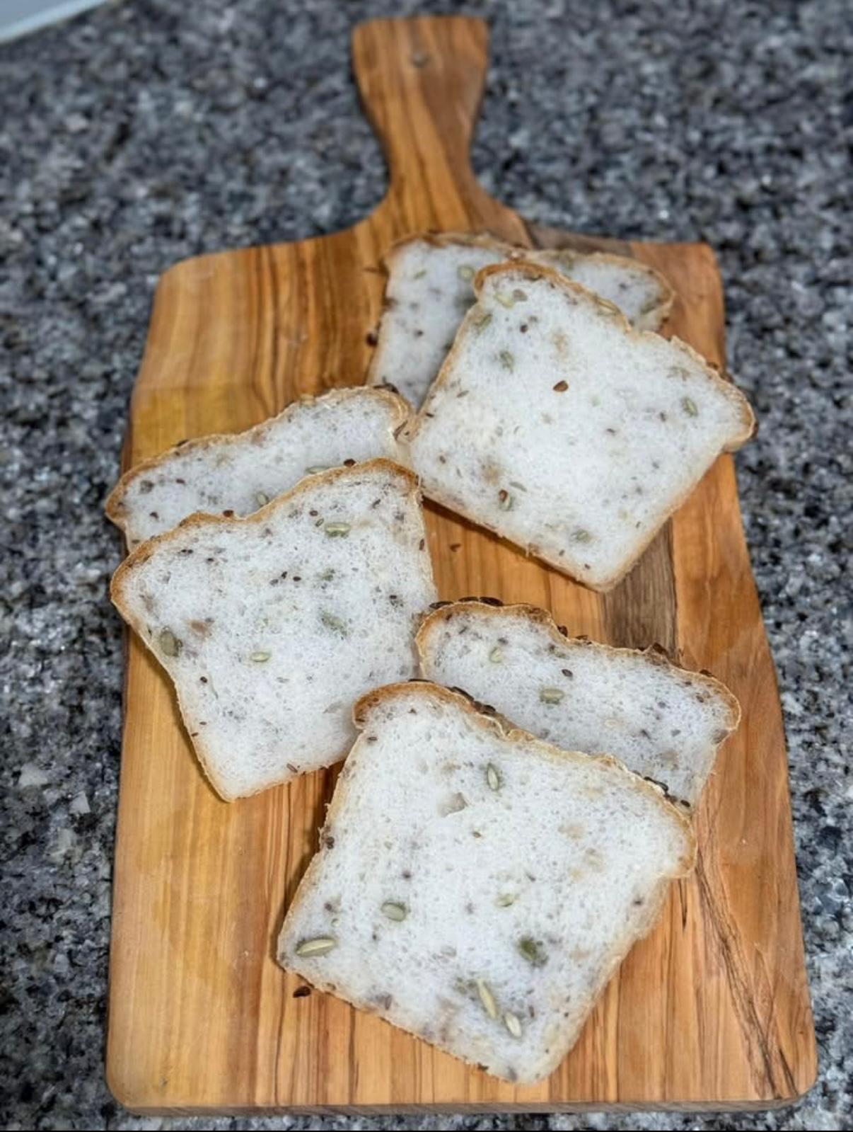 Freshly sliced gluten-free seeded loaf on a wooden board