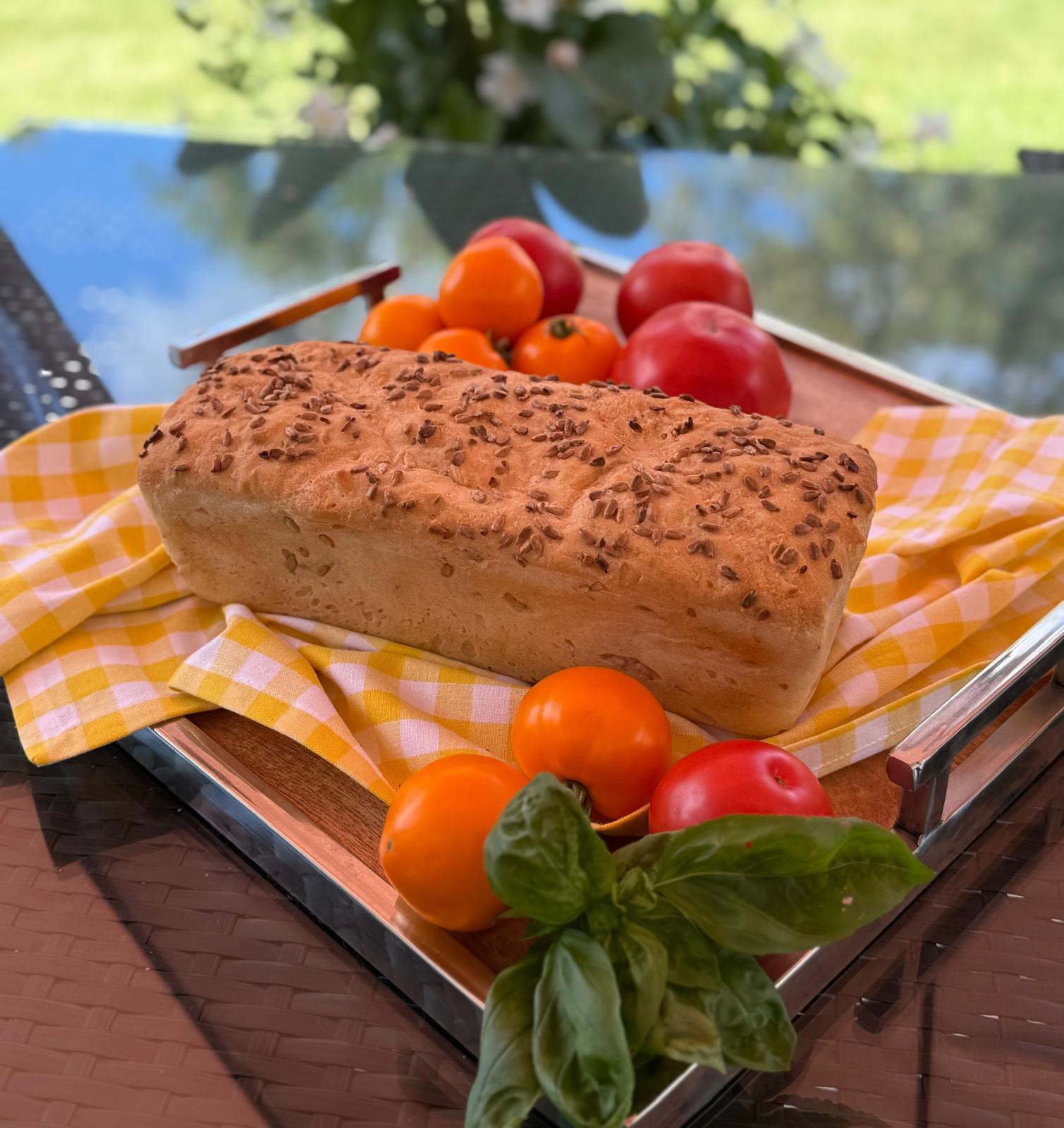 Gluten-free seeded loaf styled with tomatoes and fresh basil