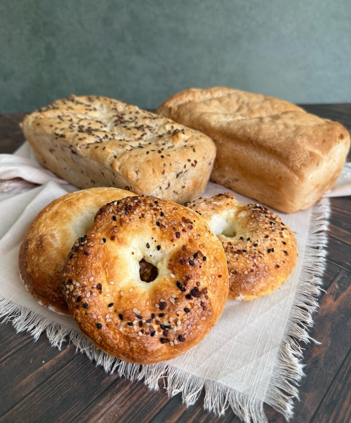 Fresh gluten-free loaves and everything bagels on a linen cloth